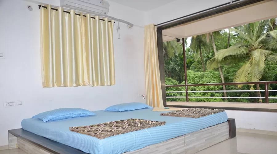AC room with large window and balcony overlooking coconut palms